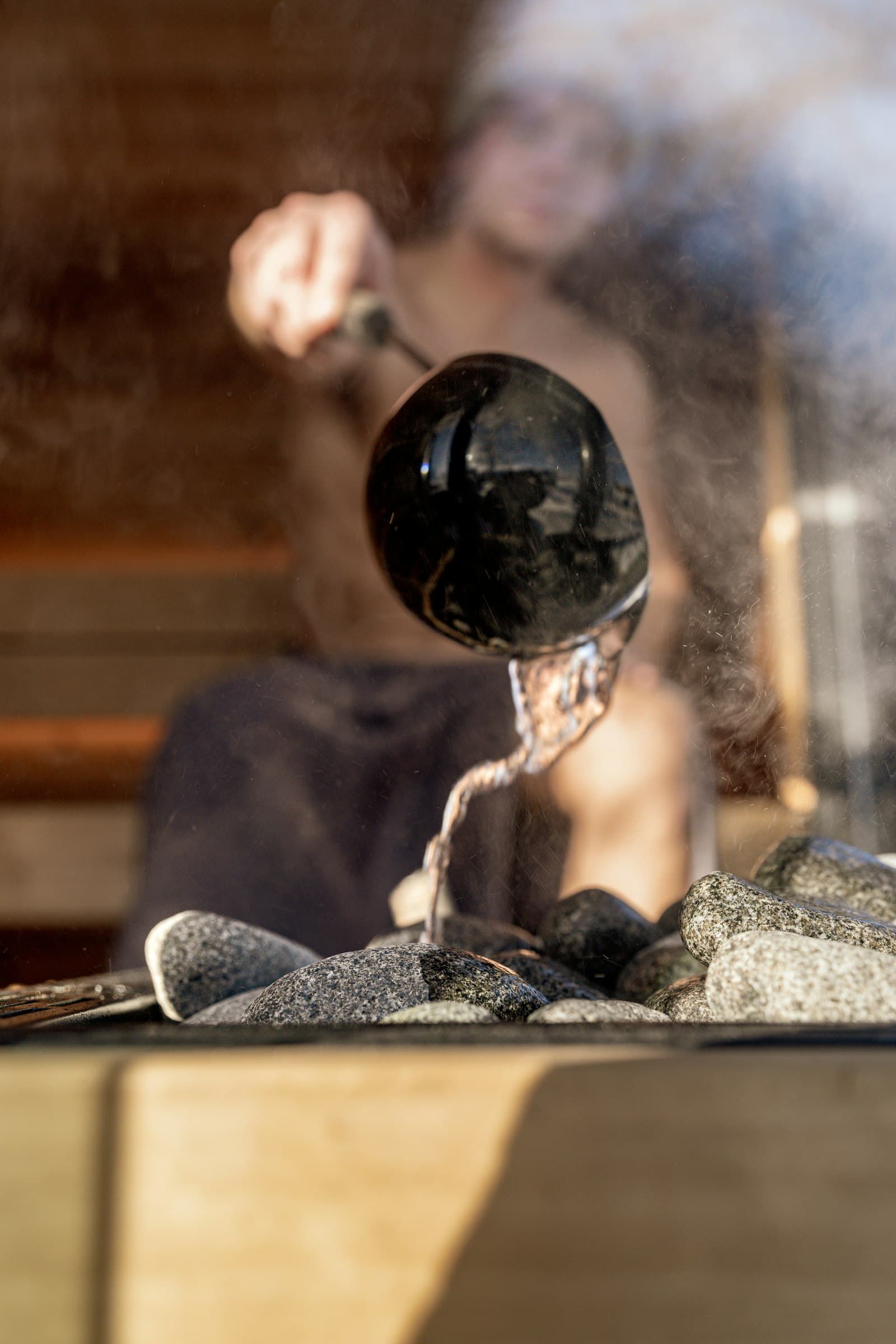 Steam rising as water is poured over hot sauna stones