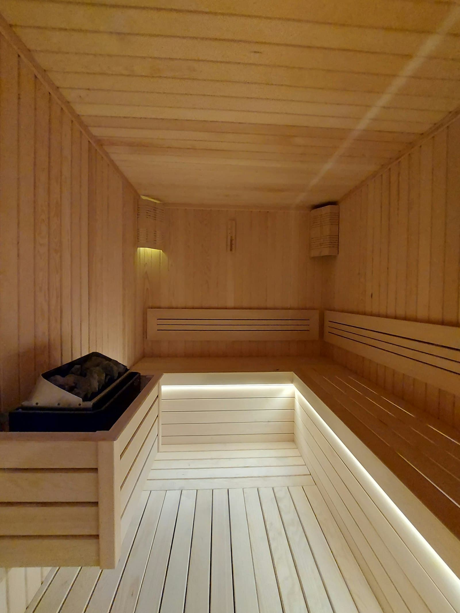 Bright modern wooden sauna interior with heater and benches