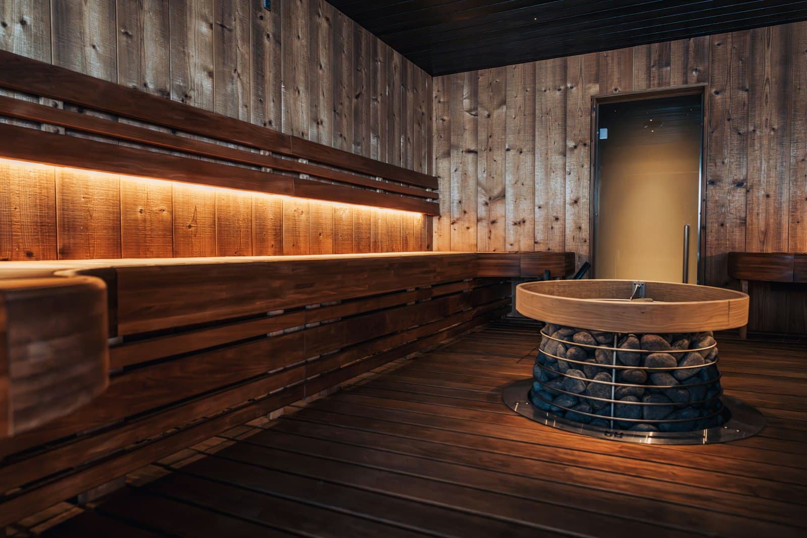 Moody sauna interior with a central stone heater and dark wood